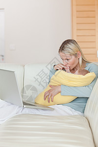 母亲在抱着婴儿时看着她的笔记本电脑图片
