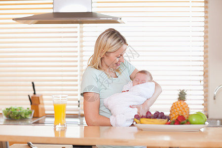 妇女把睡着的婴儿抱在厨房里图片