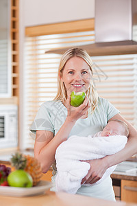 母亲怀着孩子的婴儿 在她的手臂上有一个苹果图片