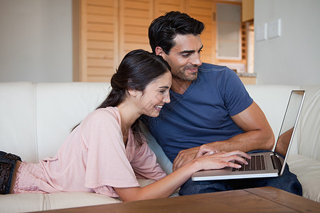 使用笔记本电脑微笑的年轻夫妇女性喜悦网络团结上网互联网闲暇客厅技术沟通图片