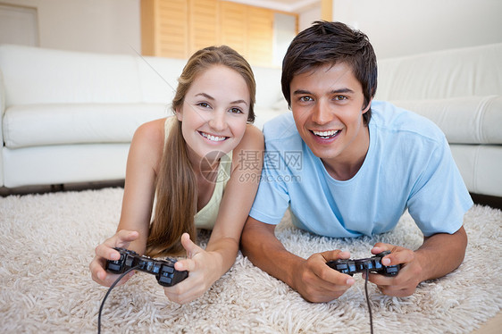 玩电子游戏的微笑情侣女性享受成功妻子快乐安慰乐趣沙发长椅房子图片