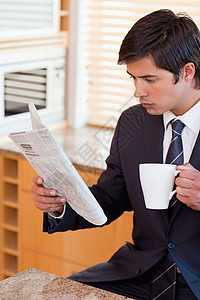 一名商务人士在看新闻时喝茶的肖像图片