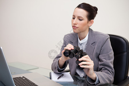 办公桌上有望远镜的女商务人士图片