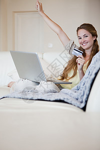 沙发上的女人庆祝她赢得了网上拍卖会背景图片