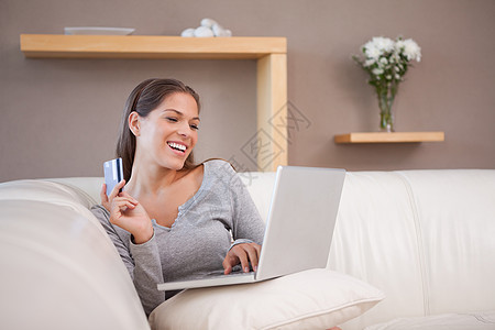 微笑的女人在沙发上网上购物图片