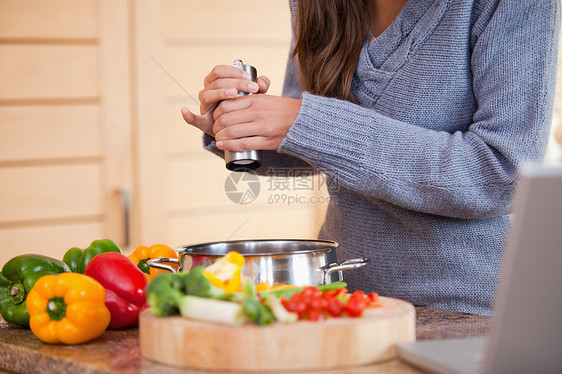 女人在蔬菜炖菜中加辣椒图片
