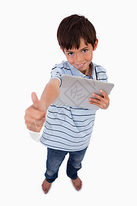 男孩使用平板电脑用拇指高举的肖像图片