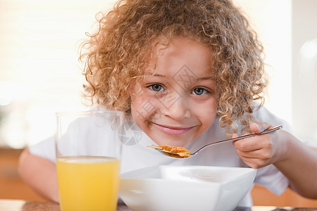 微笑的女孩吃早餐外表厨房小吃男孩们谷物勺子营养果汁玻璃橙子图片