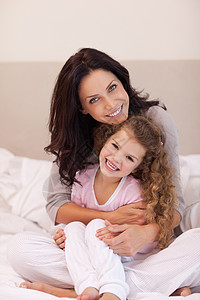 母亲拥抱她的女儿时间枕头幸福团结女性乐趣说谎闲暇感情两个人图片