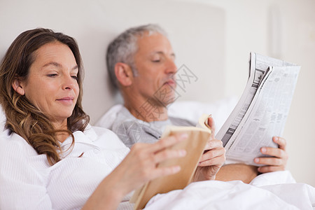 女人在看书 而她丈夫正在看新闻图片