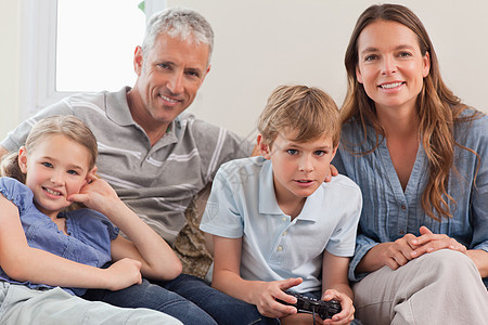 玩电子游戏的家庭男孩们房子微笑女孩们儿子兄弟童年闲暇沙发控制器图片