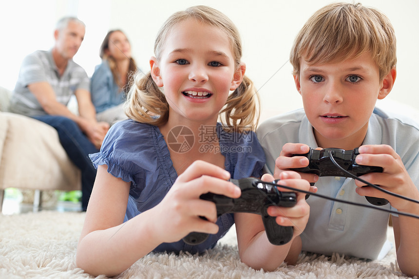 玩游戏的兄弟姐妹们与父母在b上玩电子游戏图片