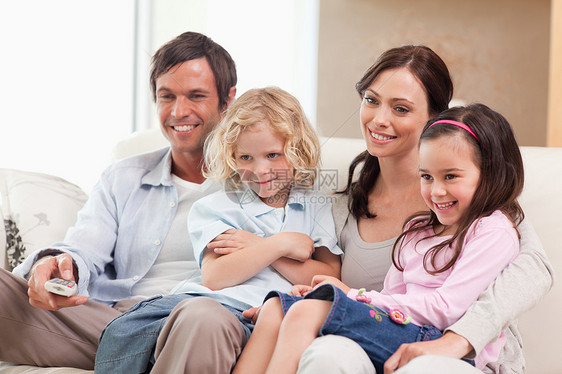 一起看电视的微笑的家庭在一起笑图片