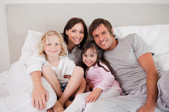 幸福的家庭在床上摆姿势感情享受女性父亲卧室儿子睡衣拥抱母亲说谎图片