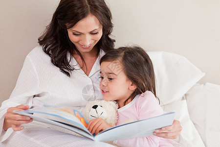 妈妈读一个故事给女儿听睡衣阅读生活卧室家长想像力童年教育享受母亲图片