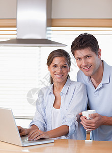 一对夫妇在喝咖啡时使用笔记本电脑的肖像中年人丈夫饮料阅读团结技术男人幸福杯子冲浪图片