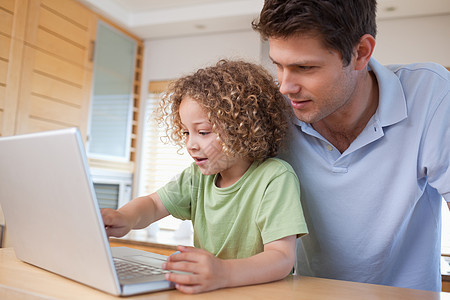 男孩和他父亲用笔记本幸福电脑互联网微笑童年技术房间两个人冲浪教育图片