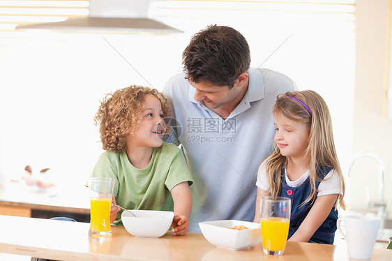 父亲和孩子在吃早餐时微笑的父亲与子女一起微笑图片