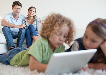 在父母幸福时使用平板电脑使可爱的孩子更可爱图片
