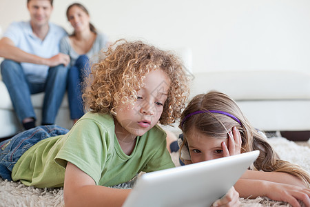 年幼儿童在父母幸福时使用平板电脑;图片