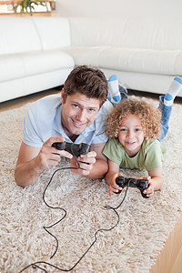 一个男孩和他父亲玩电子游戏的肖像乐趣快乐中年人两个人童年男人软垫地面家庭视频图片