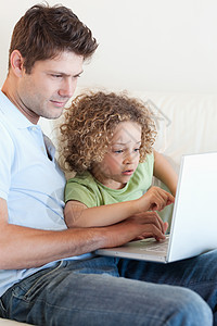 使用笔记本电脑对一个小男孩和他父亲的肖像图片