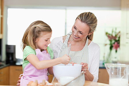 母亲和女儿在厨房玩得开心中年人食物乐趣面粉女孩喜悦烘烤女士面团准备图片