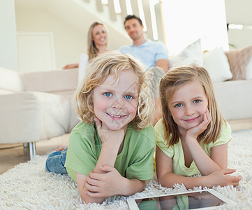 儿童在毯子上 用石板和父母坐在他们的身后图片