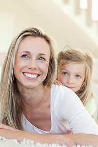 母亲和女儿在地板上微笑孩子客厅家庭女孩感情地面享受拥抱中年人童年图片