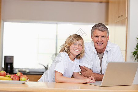 父亲和儿子用笔记本电脑微笑图片