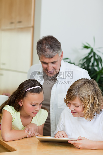 男孩用平板电脑向姐姐和父亲展示东西图片