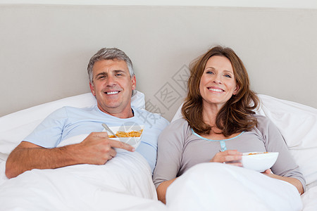 一对夫妇在床上吃麦片图片