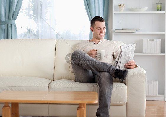 男人在看新闻时喝咖啡微笑娱乐闲暇房间咖啡报纸生活白色外表杯子图片