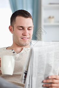 一个微笑的男人在看新闻时喝咖啡的肖像图片