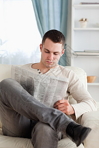 男人看报纸的肖像年轻人享受长椅衬衫白色阅读房间闲暇水平休息室图片