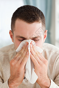 一个年轻人吹鼻涕的肖像卫生疾病长椅衬衫流感喷嚏手帕外表保健组织图片