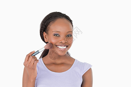 在白色背景下用化妆刷子贴近女性的近身图片