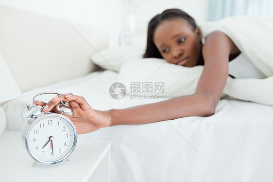 女人把闹钟关了卧室苏醒手臂房间女性噪音枕头警报压力刺激性图片