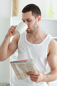 一名年轻男子在看新闻时喝茶的肖像图片