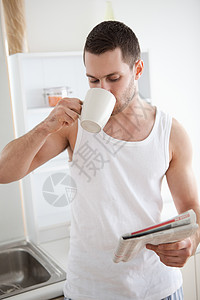 一位微笑的男人在看新闻时喝茶的肖像图片