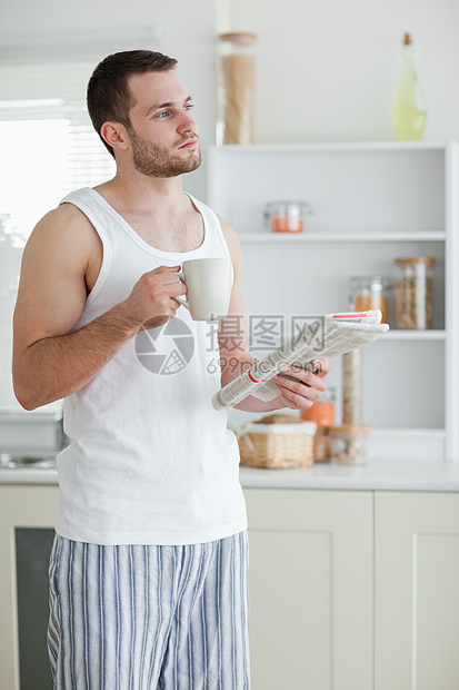 一名运动男子在看新闻时喝茶的肖像图片