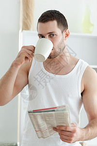 一位英俊男子在看新闻时喝茶的肖像图片