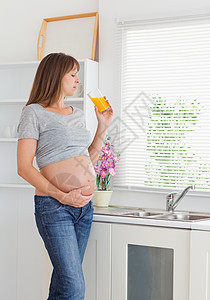 有吸引力的孕妇在喝杯橙汁的同时 饮一杯橙汁图片