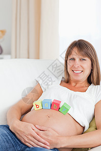 可爱的孕妇在躺着时用木木木板玩耍妈妈男生几个月客厅沙发生活母性立方体母亲说谎图片
