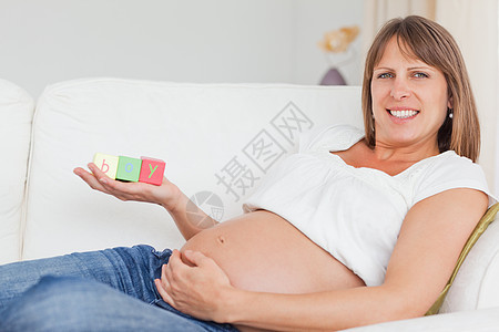 美丽的孕妇在玩木木砖和有t的游戏长椅幸福生活母性喜悦玩具情感享受母亲客厅图片