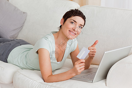 幸福的妇女在网上购物女士相机电脑女性房间顾客长椅互联网房子技术图片