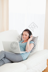 有魅力的女性 耳机在她的笔记本电脑上放松图片