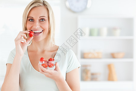 一个年轻女人吃草莓的近身小吃活力饮食午餐厨房女士水果女性重量营养图片