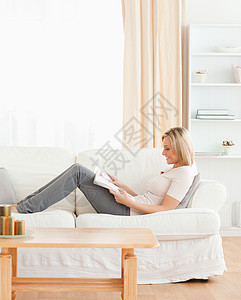 妇女阅读杂志的肖像思维裙子冒充金发女郎微笑喜悦乐趣房子身体沙发图片