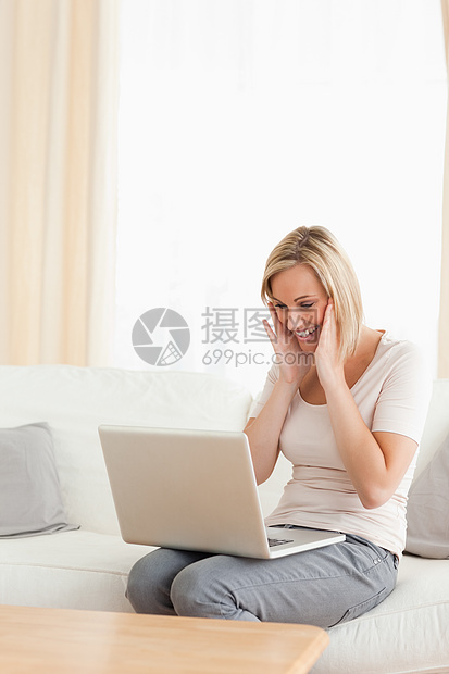 一个快乐的女人看着她的笔记本电脑的肖像图片